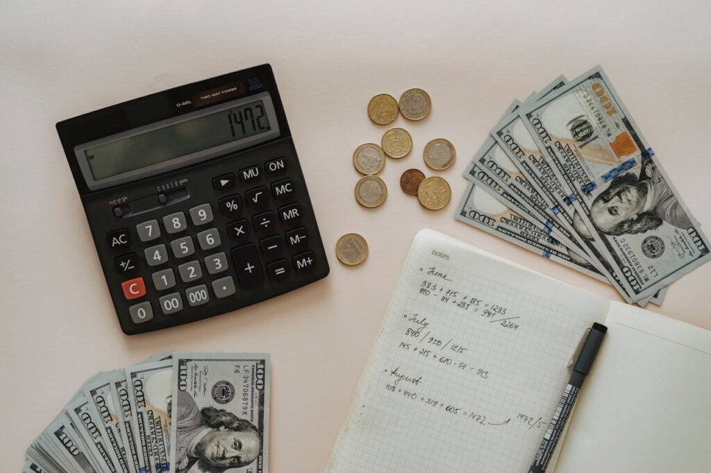 Black Calculator beside Coins and Notebook